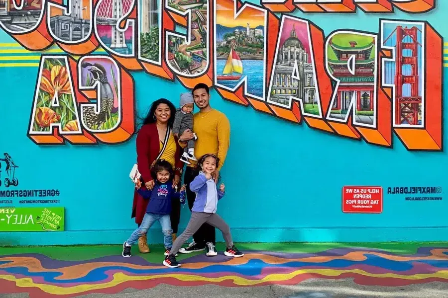一个家庭在贝博体彩app壁画前摆姿势拍照
