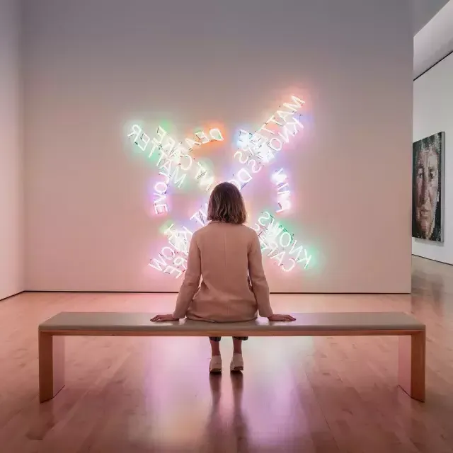 Une femme, assise sur un banc, regarde une œuvre d’art lumineux contemporain au SF MOMA à San Francisco.
