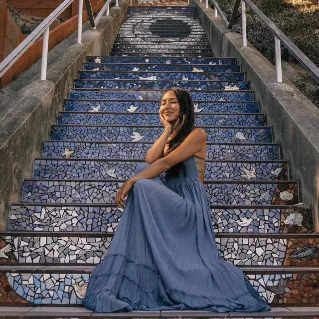 Une femme pose assise sur les escaliers carrelés de la 16e Avenue dans le quartier Sunset de San Francisco.