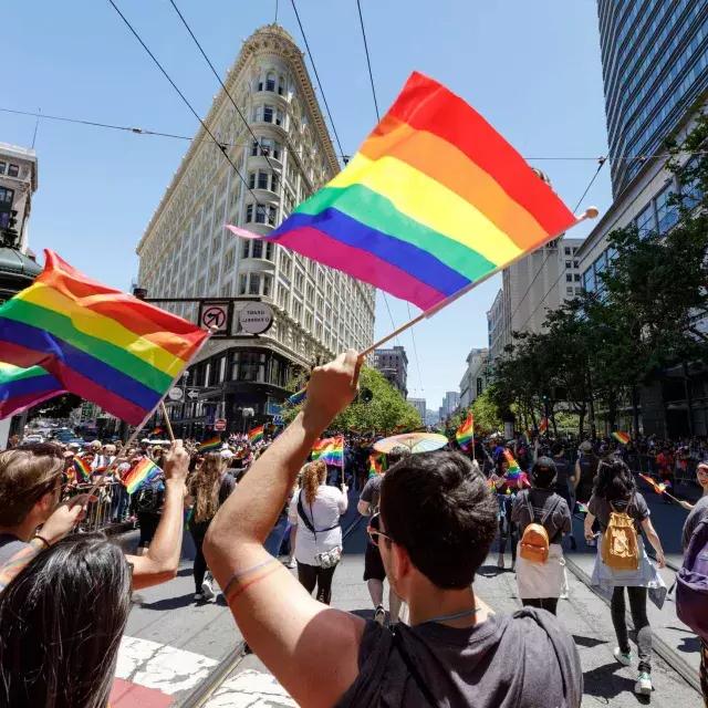샌프란시스코 프라이드 퍼레이드를 걷는 사람들은 무지개 깃발을 흔들고 있습니다.